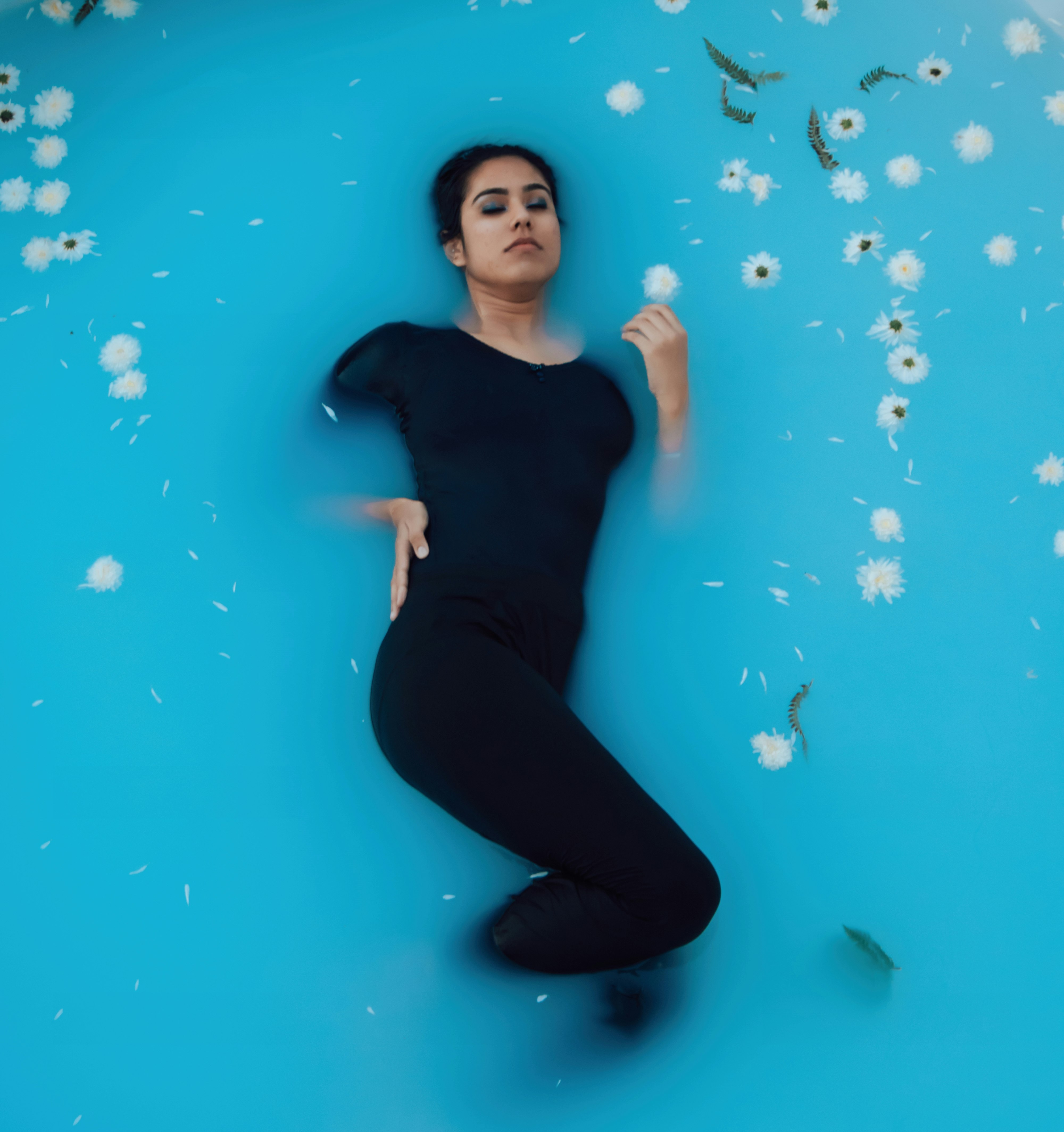 woman in black tank top and black pants sitting on blue water